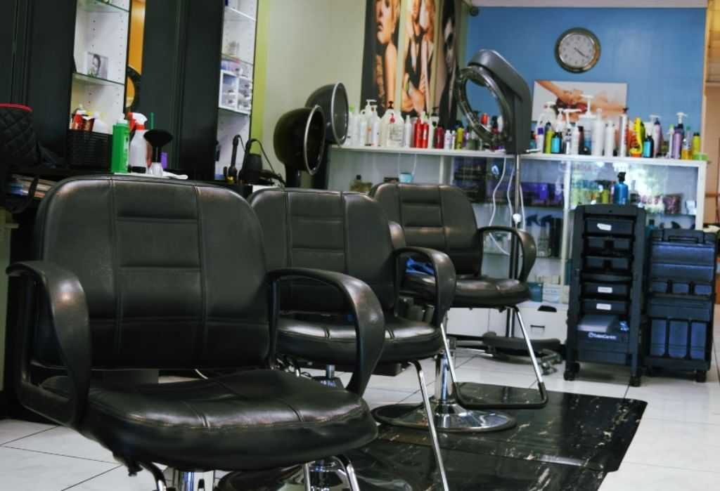 Barbershop interior with empty black chairs and shelves of hair products.